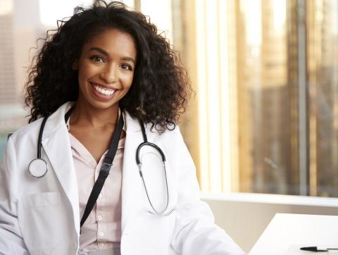 Portrait Of Smiling Female Doctor Wearing White Coat With St