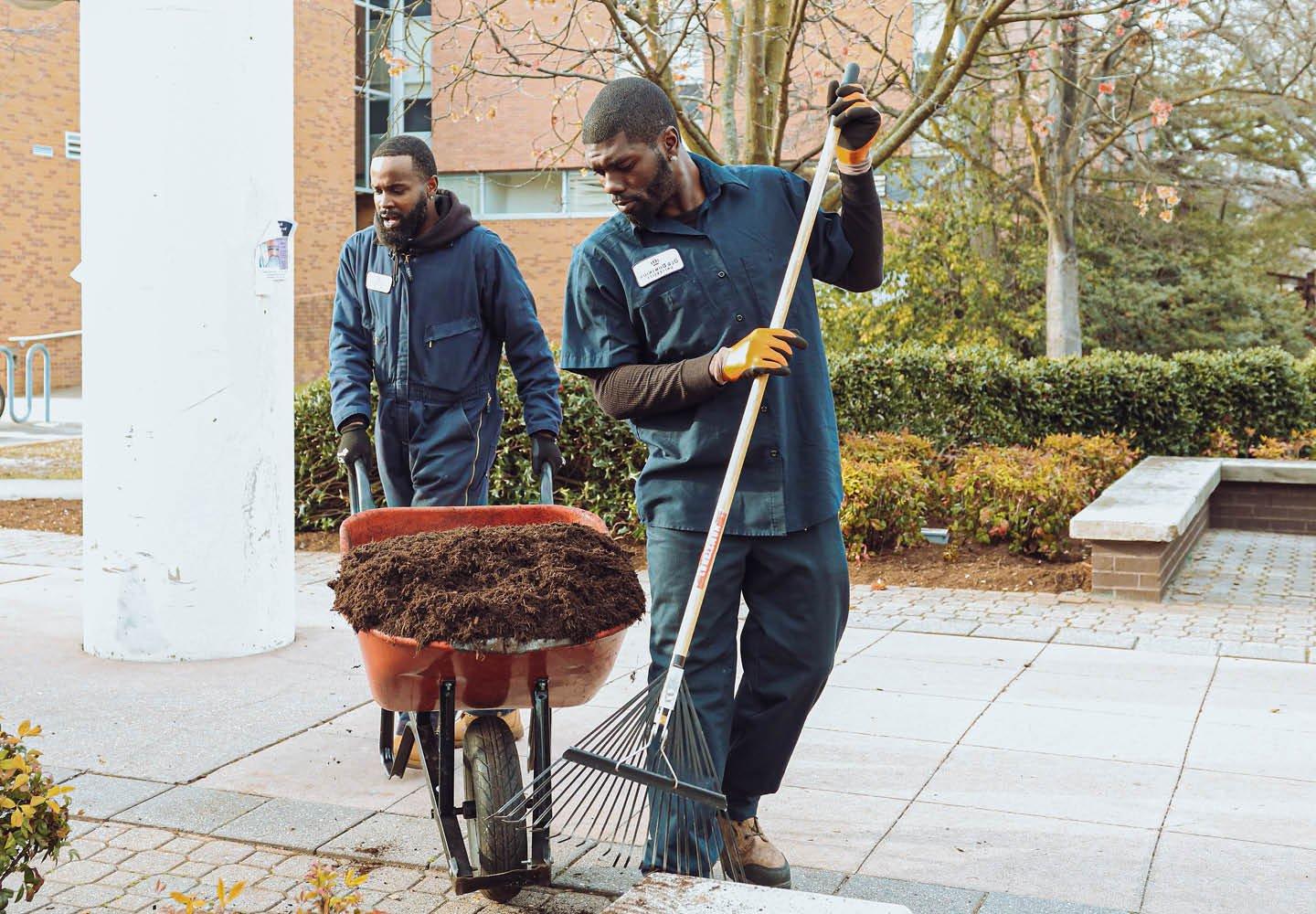 Two grounds workers tending landscape.